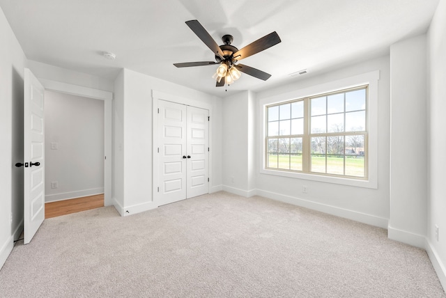 unfurnished bedroom with light carpet, a closet, and ceiling fan