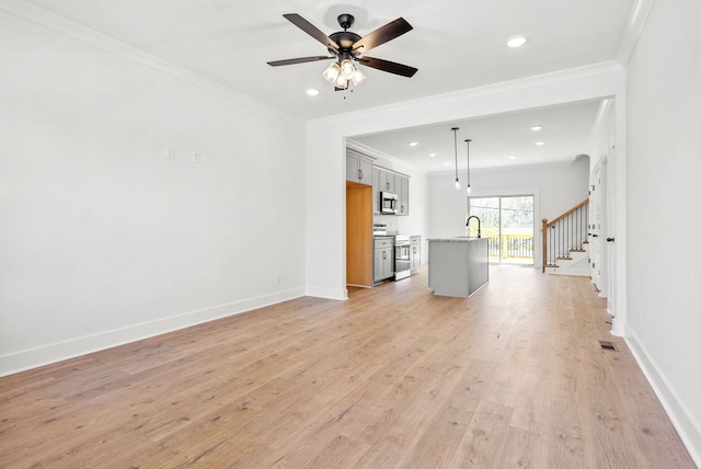 unfurnished living room featuring light hardwood / wood-style flooring, ceiling fan, crown molding, and sink