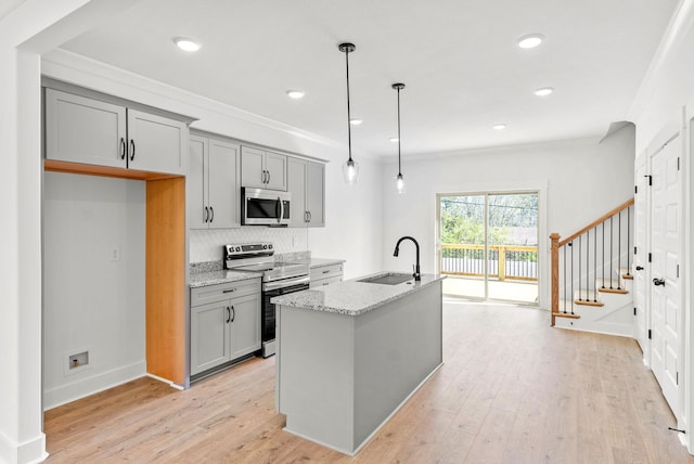 kitchen with sink, gray cabinets, light stone countertops, decorative light fixtures, and stainless steel appliances