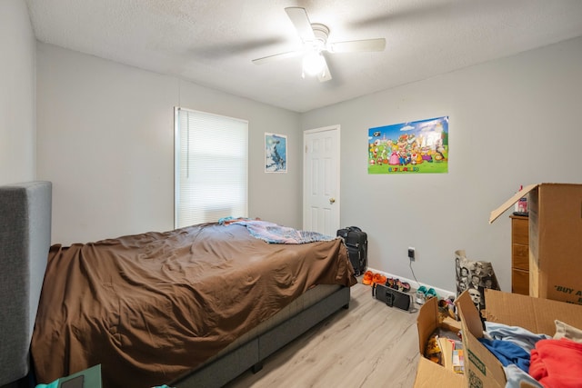 bedroom featuring ceiling fan, hardwood / wood-style floors, and a textured ceiling