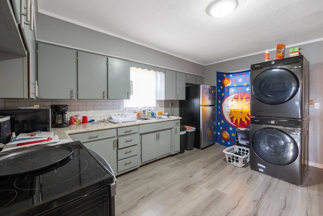 kitchen with stainless steel fridge, electric range, ornamental molding, and stacked washer / drying machine