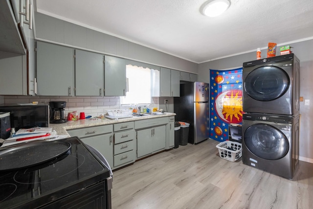 41 E 7th St, Parsons, TN 38363 - kitchen featuring stacked washer / dryer, freestanding refrigerator, electric range, light wood-type flooring, and light countertops