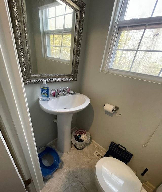 bathroom featuring tile patterned flooring, toilet, and a wealth of natural light