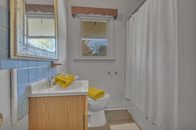 full bathroom featuring tasteful backsplash, vanity, shower / bath combo with shower curtain, hardwood / wood-style floors, and toilet