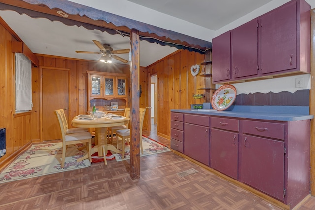 kitchen featuring dark parquet flooring, ceiling fan, and wooden walls