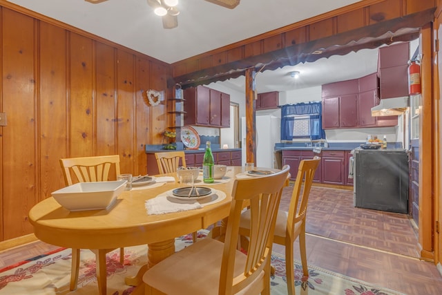 dining space featuring wooden walls, ceiling fan, and parquet flooring