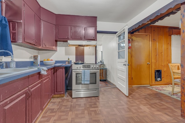 kitchen with wood walls, light parquet floors, stainless steel range with electric cooktop, and sink