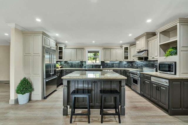 kitchen featuring a breakfast bar area, light stone counters, a kitchen island, and high end appliances