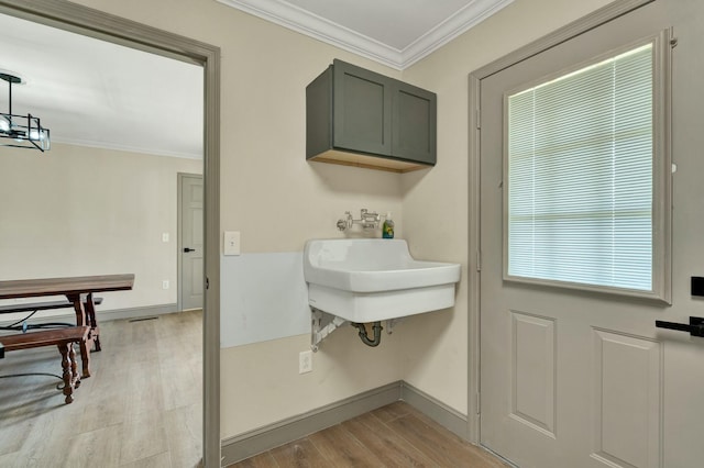 clothes washing area with light hardwood / wood-style floors and crown molding