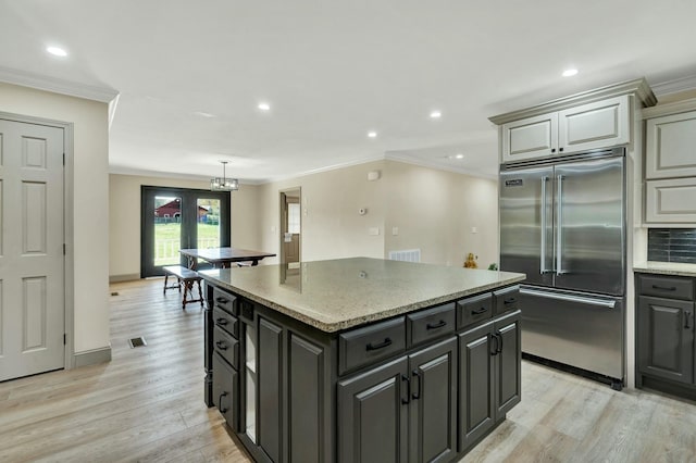 kitchen with built in fridge, light hardwood / wood-style flooring, a kitchen island, and light stone countertops