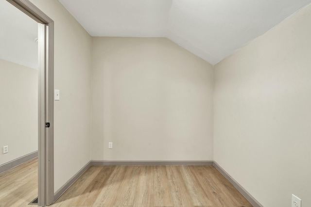 spare room with light hardwood / wood-style floors and lofted ceiling