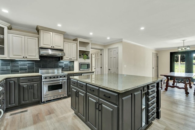 kitchen with light wood-type flooring, cream cabinets, a center island, and stainless steel appliances