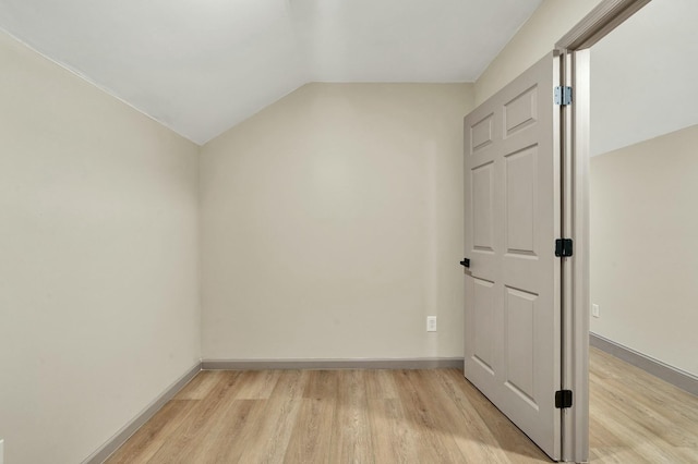 empty room with light hardwood / wood-style flooring and lofted ceiling