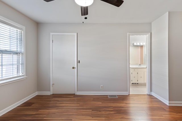 unfurnished bedroom featuring dark hardwood / wood-style flooring, ensuite bath, ceiling fan, and sink