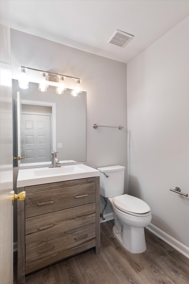 bathroom with toilet, vanity, and hardwood / wood-style flooring