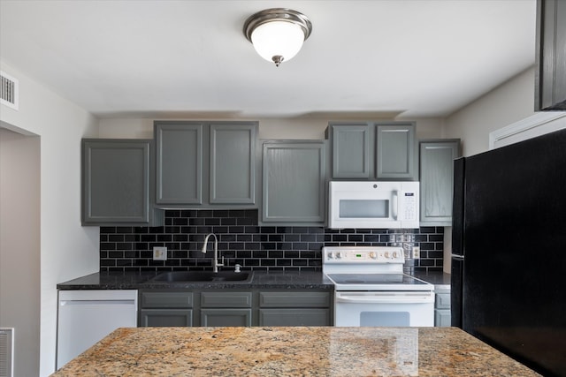 kitchen with white appliances, gray cabinets, dark stone countertops, and sink