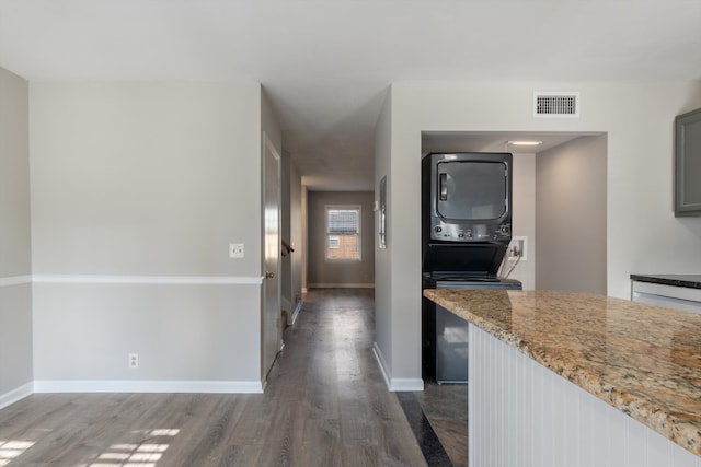 hall featuring stacked washer / dryer and dark hardwood / wood-style floors