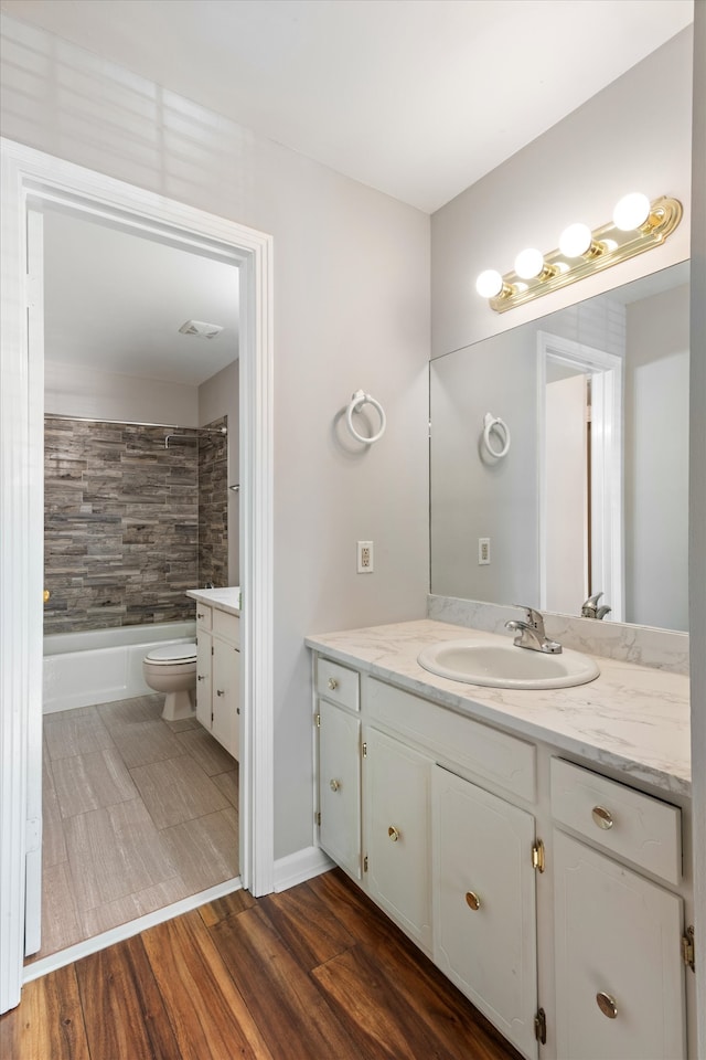 full bathroom with hardwood / wood-style flooring, tiled shower / bath combo, toilet, and vanity