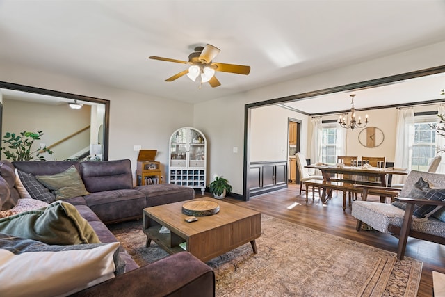 living room with plenty of natural light, dark wood-type flooring, and ceiling fan with notable chandelier