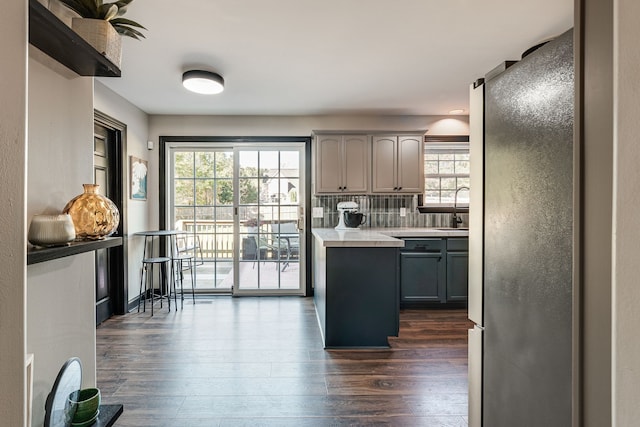 kitchen featuring a center island, sink, dark hardwood / wood-style flooring, gray cabinets, and decorative backsplash