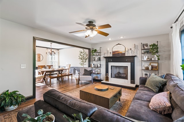 living room with ceiling fan with notable chandelier and hardwood / wood-style flooring