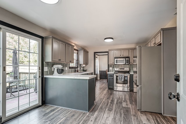 kitchen with backsplash, stainless steel appliances, dark wood-type flooring, and gray cabinetry