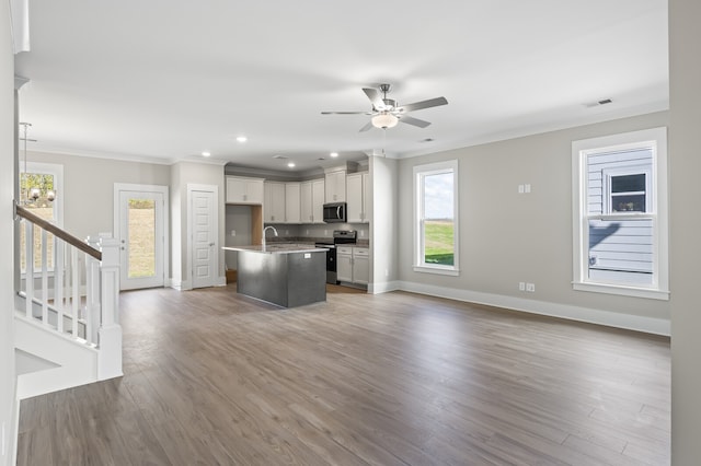 kitchen featuring hardwood / wood-style floors, a center island with sink, ornamental molding, decorative light fixtures, and stainless steel appliances