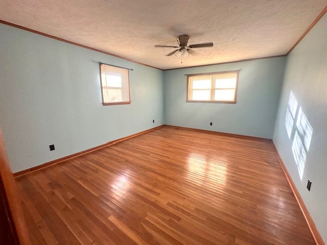 unfurnished room featuring wood-type flooring, a textured ceiling, ceiling fan, and ornamental molding