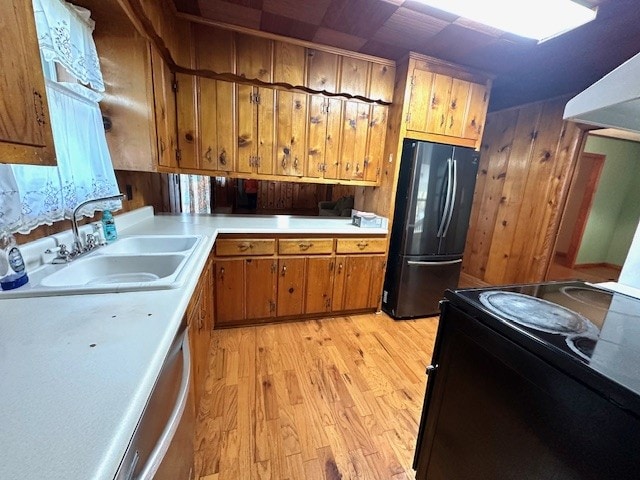 kitchen featuring exhaust hood, sink, black appliances, and light hardwood / wood-style floors