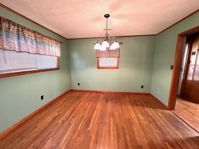 spare room featuring ornamental molding, wood-type flooring, a textured ceiling, and a chandelier