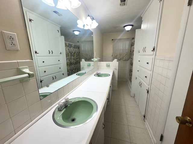 bathroom with tile patterned flooring, vanity, tile walls, and curtained shower