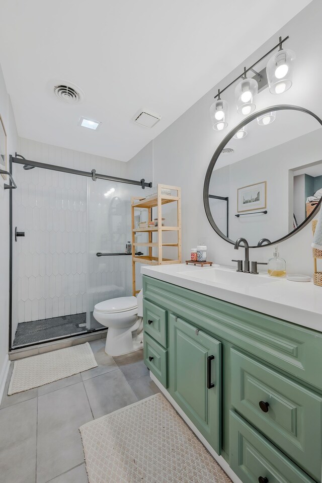 bathroom with tile patterned flooring, vanity, tiled shower, and toilet