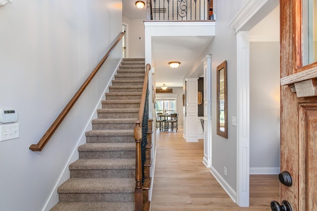 foyer entrance featuring stairs, light wood-type flooring, and baseboards