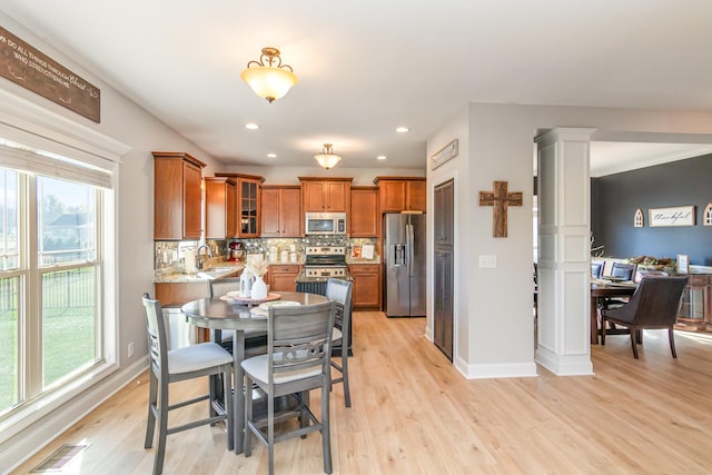 dining room with baseboards, light wood-type flooring, visible vents, and ornate columns