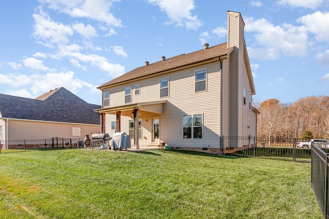 rear view of house with a yard, a chimney, a patio area, and a fenced backyard