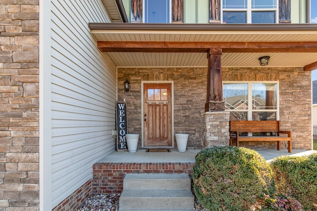 entrance to property with covered porch and stone siding