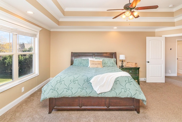 bedroom with light colored carpet, a ceiling fan, baseboards, a tray ceiling, and crown molding