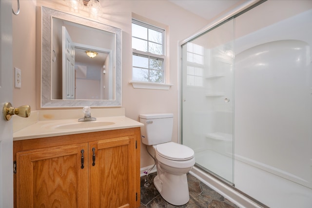 bathroom with a shower with door, vanity, and toilet