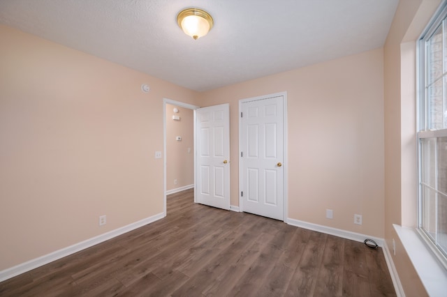 unfurnished bedroom with a textured ceiling and dark hardwood / wood-style floors