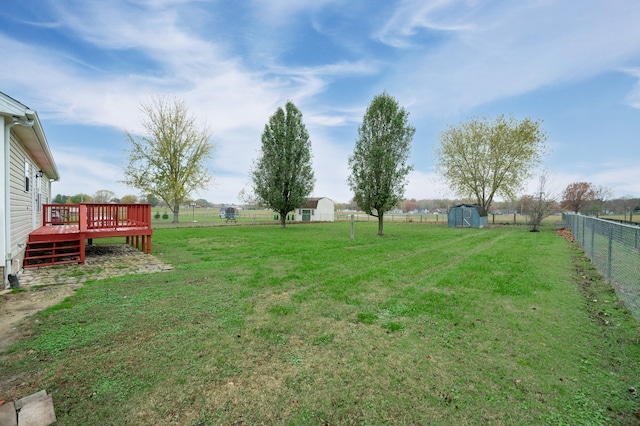 view of yard with a rural view, a shed, and a wooden deck