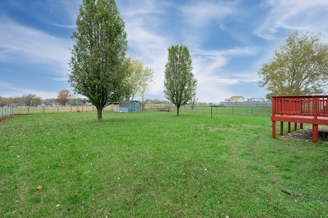 view of yard featuring a rural view, a deck, and a storage shed