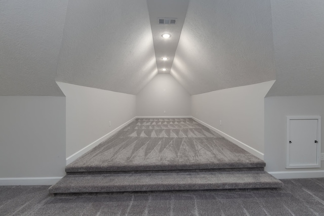 staircase featuring carpet flooring, a textured ceiling, and vaulted ceiling