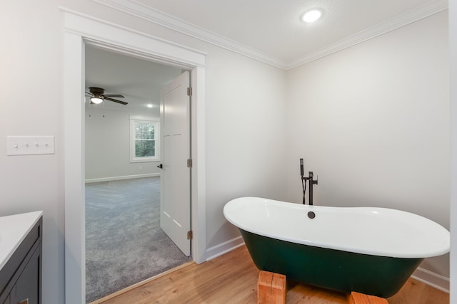 bathroom with ceiling fan, a bath, wood-type flooring, vanity, and ornamental molding