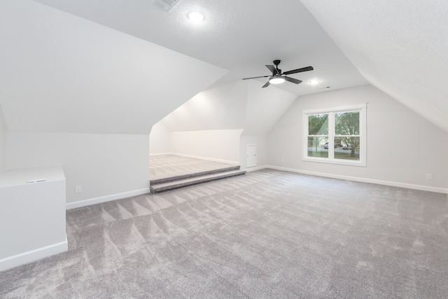 additional living space with light carpet, a textured ceiling, ceiling fan, and lofted ceiling