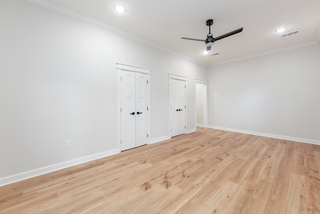 unfurnished bedroom with ceiling fan, light wood-type flooring, crown molding, and multiple closets