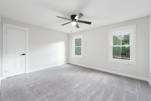 carpeted spare room featuring ceiling fan and a healthy amount of sunlight