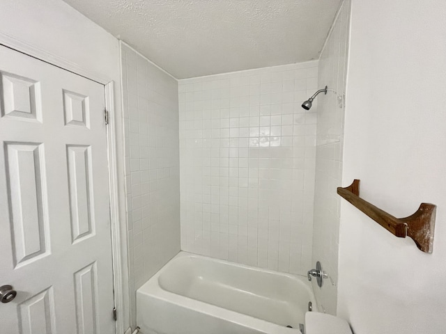 bathroom with tiled shower / bath combo and a textured ceiling