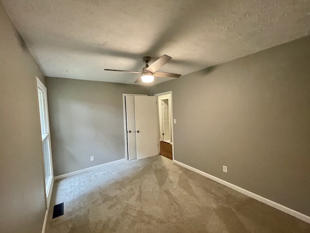 unfurnished bedroom featuring ceiling fan, carpet floors, and a textured ceiling