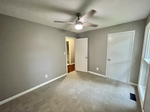 unfurnished bedroom with ceiling fan, carpet floors, a textured ceiling, and a closet