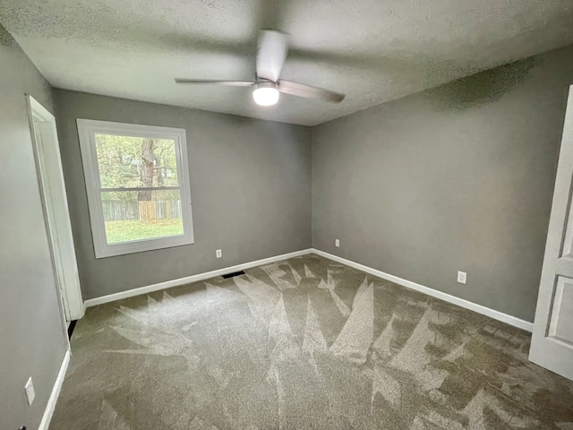 empty room with ceiling fan, dark carpet, and a textured ceiling